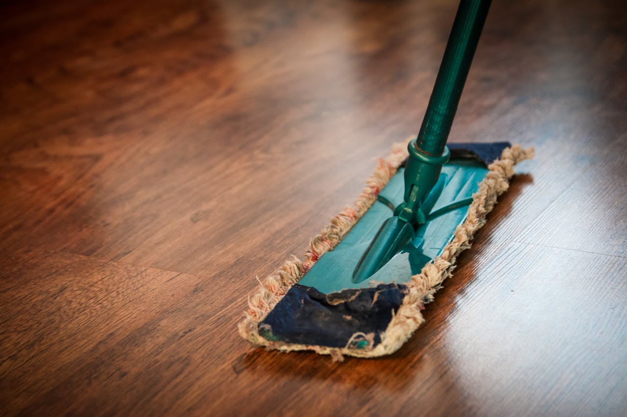 our-mission A detailed view of a mop cleaning a wooden floor, showing texture and pattern.