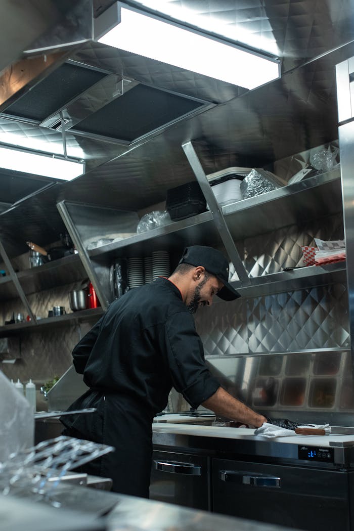 creative-approach-img Chef working in a stainless steel modern food truck kitchen, preparing a dish with focus and precision.
